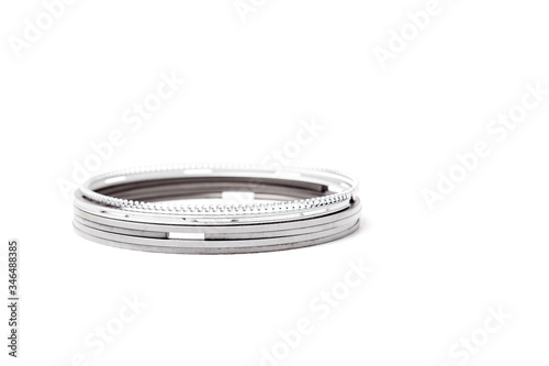 Metal chromed piston rings for car engine repair stacked on top of each other on a white isolated background in studio. Motor part spare part for sale in auto service.