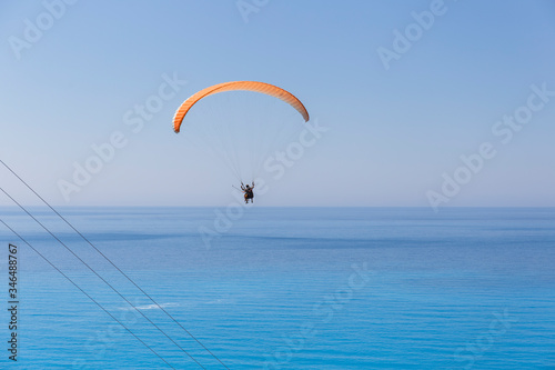 Paragliding in the sky. Paragliding tandem flying over the sea with blue water on a sunny day. Aerial view of paragliding and Ionian sea in Kefalonia, Greece. Extreme sport.