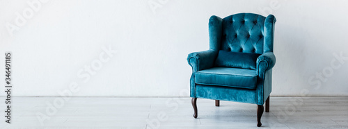 panoramic crop of blue and comfortable armchair near white wall in living room photo