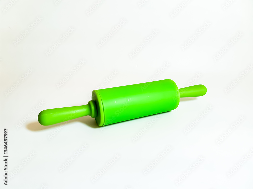 Kitchen utensils. Bright green rolling pin on a white background. 