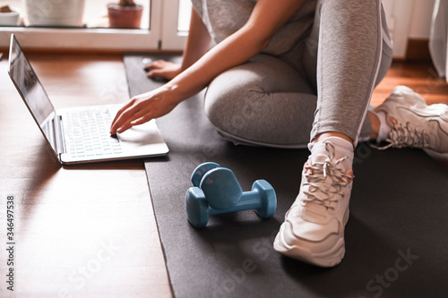 Training, Fitness At Home. Sporty man doing yoga plank while watching online tutorial on laptop, exercising in living room. woman multitasking remote work indoors lifting weights dumbbells