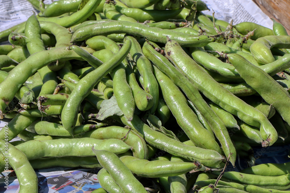 Fresh fava beans sold at a stall in a fruit and vegetable market