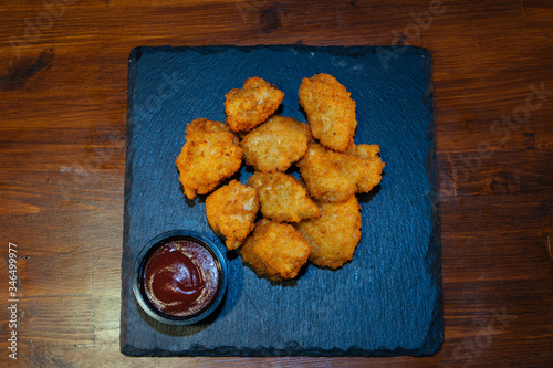 chicken or fish in breaded batter with sauce on a black stone tray