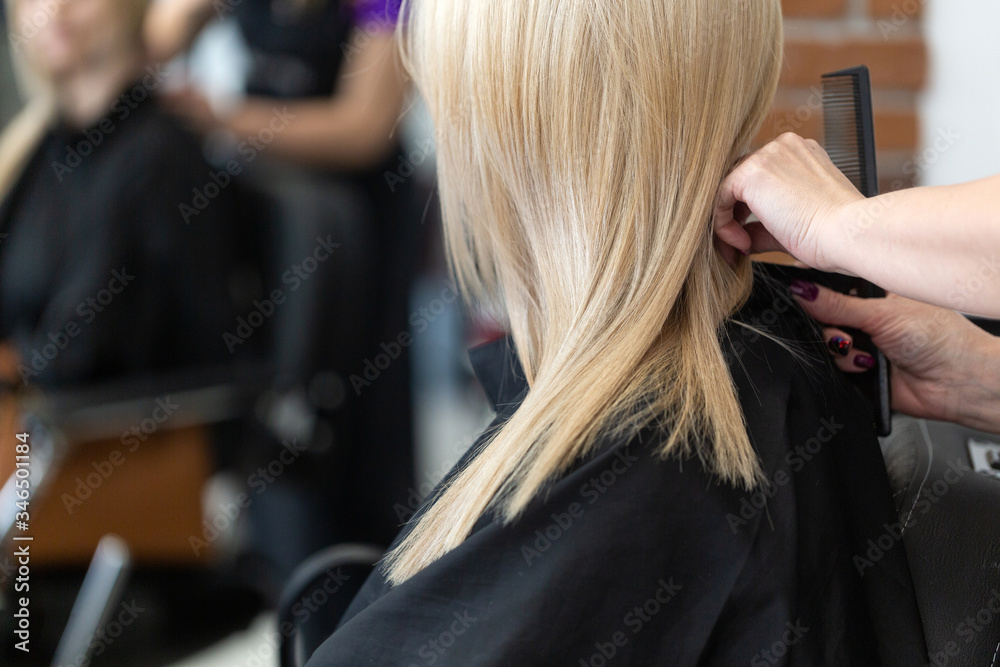 Fototapeta premium Beautiful hairstyle of young woman after dying blond hair and making highlights in hair salon.