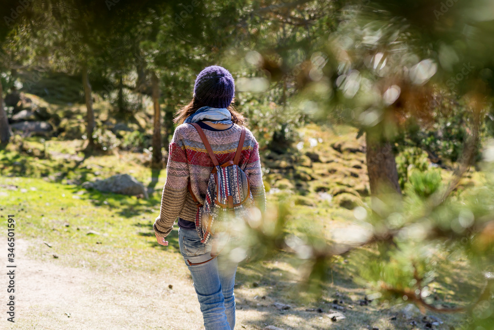 Rear view of a backpacker woman wearing a wool cap hiking