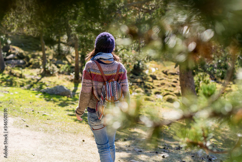 Rear view of a backpacker woman wearing a wool cap hiking © Rafa Fernandez