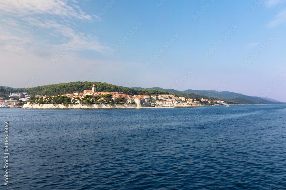 Korcula island with the old city walls, view from the sea on a sunny day in the summer blue sky. Clear adriactic sea, the south mediterranean coast of Croatia Europe. Beautiful landscape with greenery
