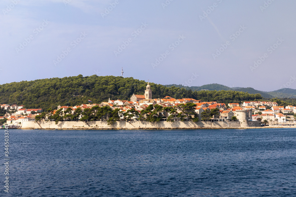 Korcula island with the old city walls, view from the sea on a sunny day in the summer.  Blue adriatic sea, the south mediterranean coast of Croatia Europe. Beautiful landscape with greenery