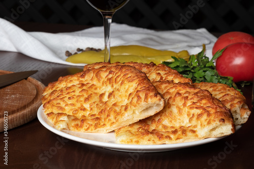 Large pieces of khachapuri with cheese on a white plate. Georgian flour product. Side view