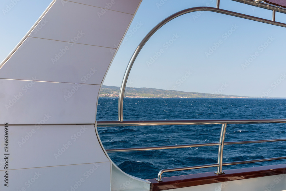 Beautiful view over the adriatic sea water shot at the deck on board of a boat with white and metal details. The waves in the water, view and the white and blue colors creating the feeling of freedom.