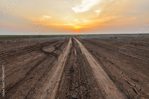 Dirt road in the parched lake with sunset sky