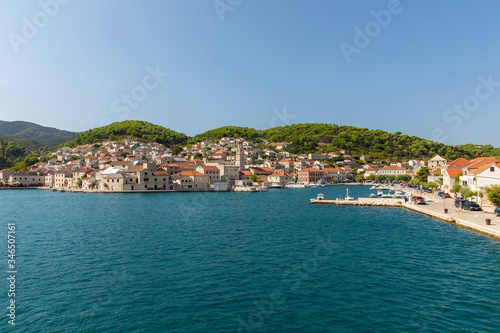 Pucisca town at Brac in Croatia, view from the sea on a sunny day in the summer. The port with it’s famous limestone from the island. Small idyllic place, village in Dalmatia.