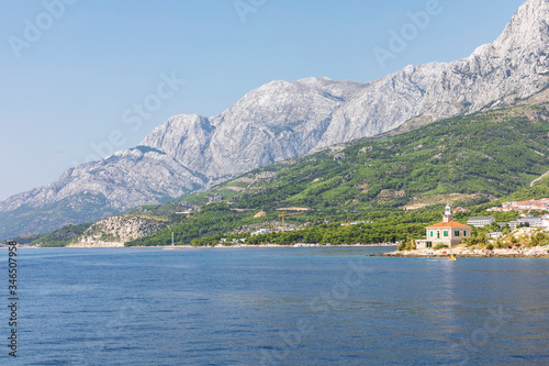 Fototapeta Naklejka Na Ścianę i Meble -  Makarska in Dalmatia, Croatia. View from the sea on a sunny day in the summer and a blue sky. A famous place with beaches. Holiday destination at the Mediterranean coast. Relaxing, sunbathing