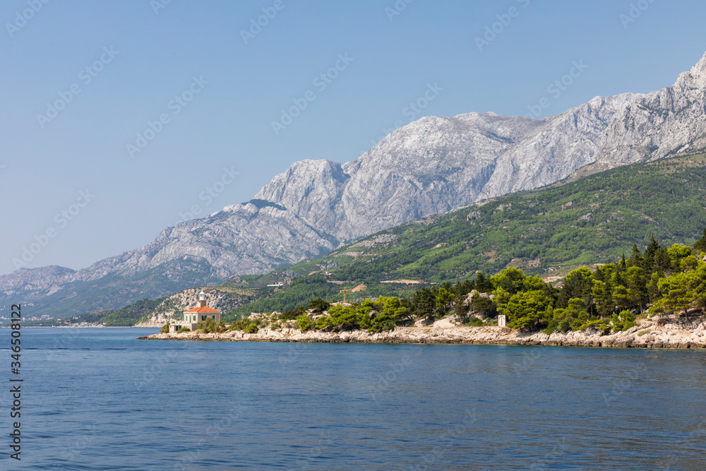 Makarska in Dalmatia, Croatia. View from the sea on a sunny day in the summer and a blue sky. A famous place with beaches and the Biokovo moutain. Holiday destination, Mediterranean coast