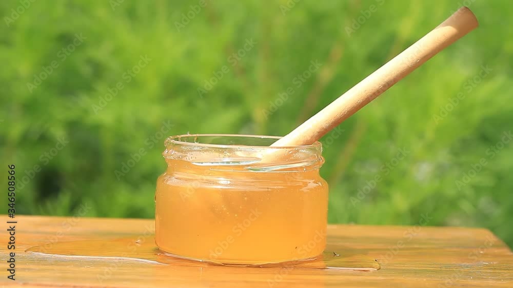 Jar and honey stick on the wooden table Jar and honey stick on the wooden table