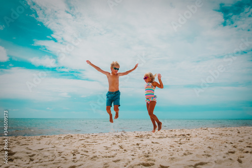 happy little boy and girl jump on beach