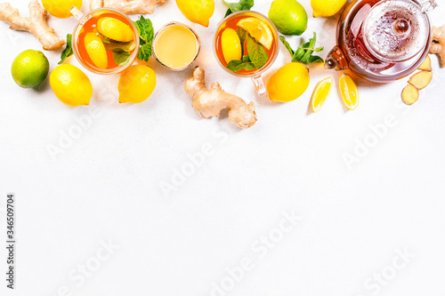 Healing black herbal tea with ginger, honey, lemon and mint. Immune booster drink in glass cup on white kitchen table background with copy space. Top view