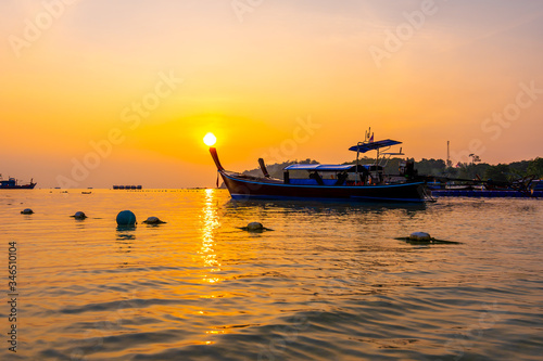 Magic sunset above small harbor with long tail boats at Ko Lipe island, Thailand. Tropical island is part of Tarutao national nature park. Soft light, concept of romantic evening in tropical paradise.