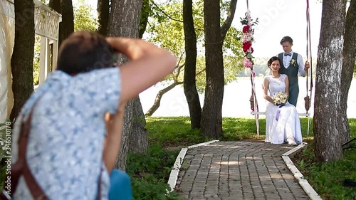 Wedding photographer taking pictures couple of newlyweds on a rope swing