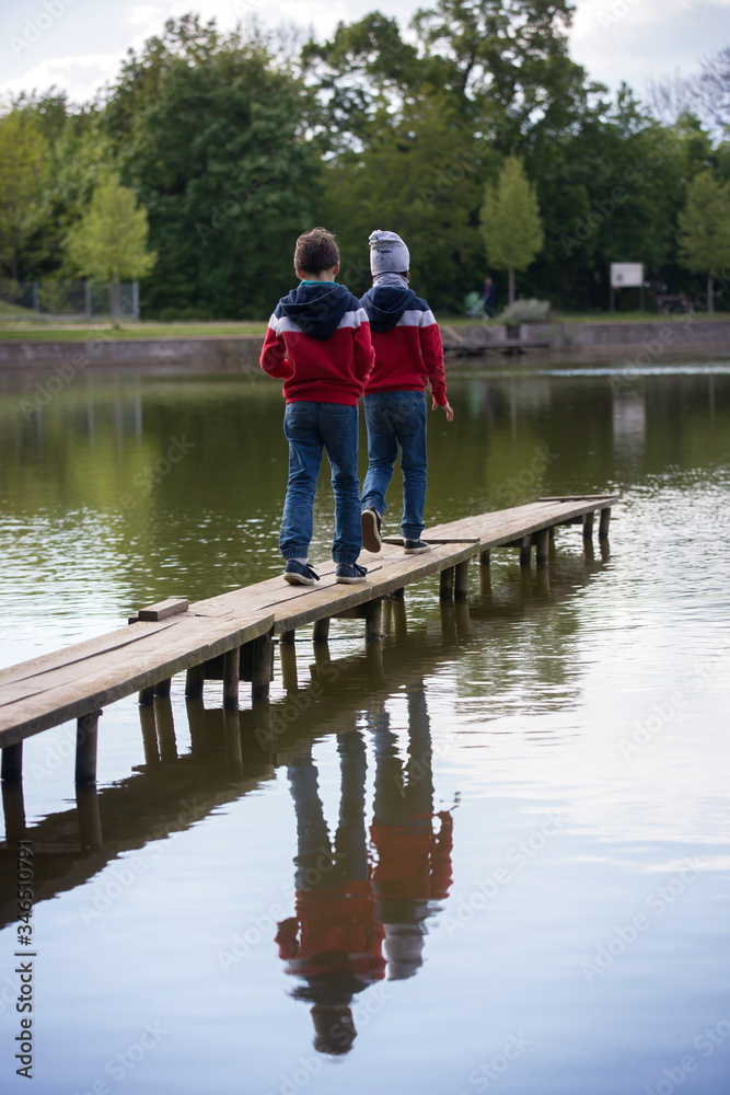 Child, boy, sitting or running on a wooden bridge over lake Child, boy, sitting or running on a wooden bridge over lake
