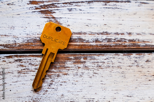 Old rusty key on wood, 'Duplicate' written on it.