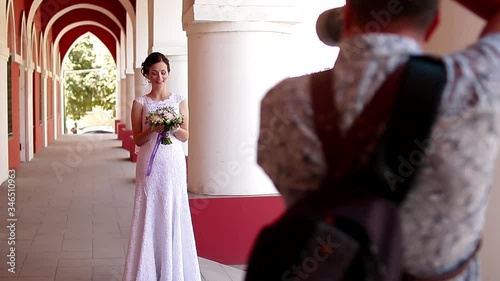 Wedding photographer taking portraits of young beautiful bride near the columns