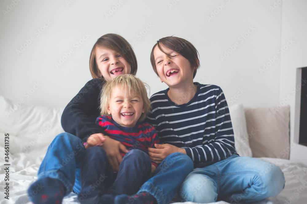 Three children, boy brothers, laughing in bed Three children, boy brothers, laughing in bed
