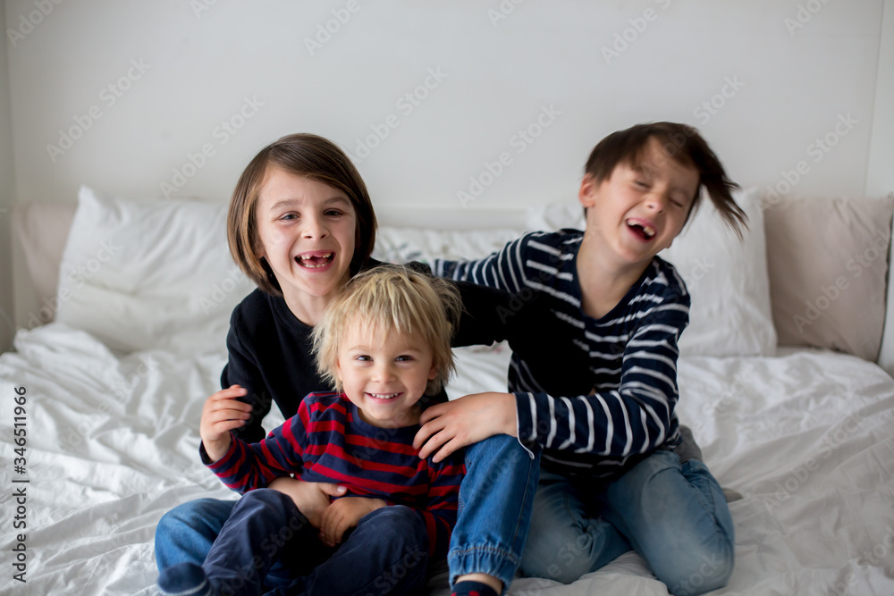Three children, boy brothers, laughing in bed Three children, boy brothers, laughing in bed