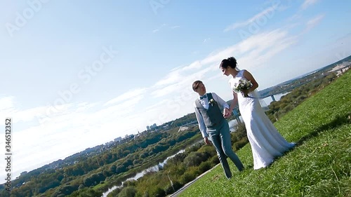 Wedding photographer taking pictures of the bride and groom on a hillside