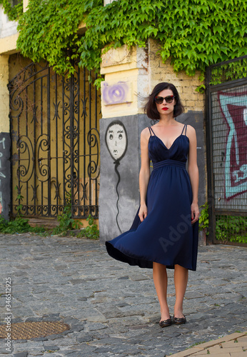 brunette in a sundress and sunglasses on a city street