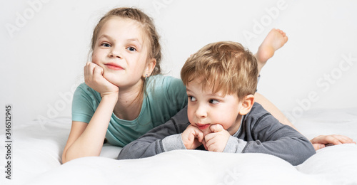 Friendship: a boy and a girl are lying on the bed propping their chin in their hand.