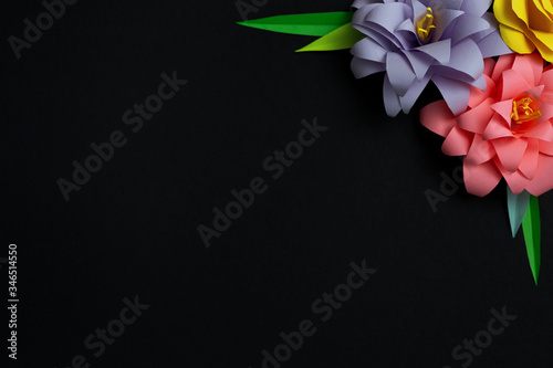 Colorful color paper flowers in the right corner on black background. Flat lay, copy space, floral art