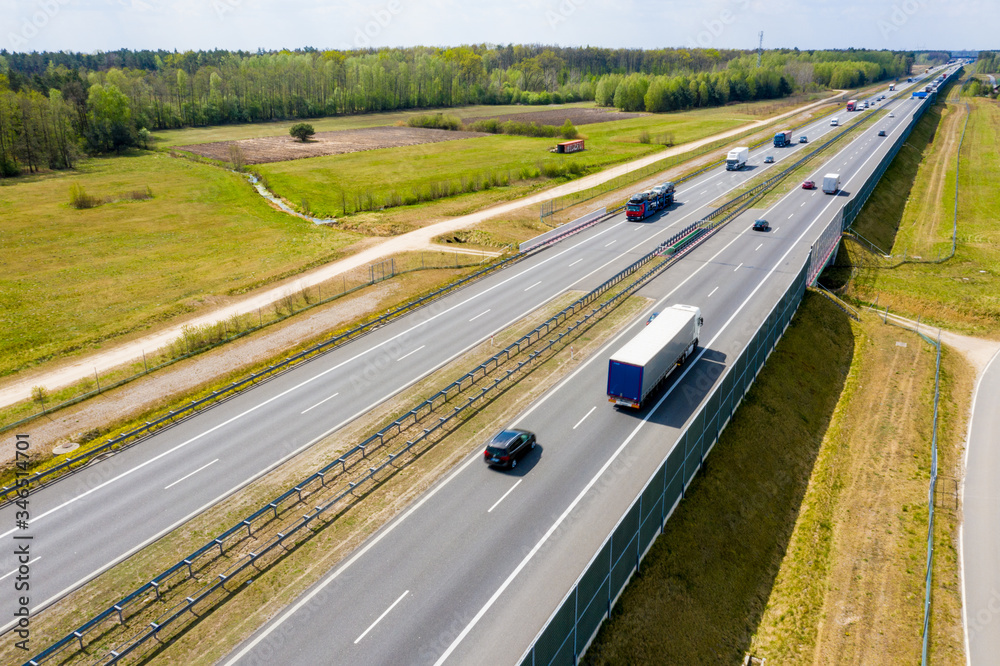  Cars and freight semi truck driving on busy highway across the country in beautiful summer evening. People on road trip traveling on busy freeway at golden sunset