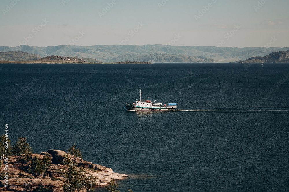 The barge is floating on the water. Beautiful photo of a lake, trees and mountains. Photo of the Bukhtarma reservoir in East Kazakhstan