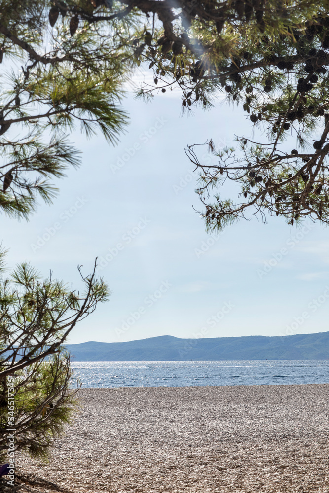 Bol beach on Brac island on a sunny day in summer. White pebbles with a clear blue Adriatic sea creating an idyllic calm scenery. Surrounded by pine trees. Relaxing, mindful, feeling of freedom Bol beach on Brac island on a sunny day in summer. White pebbles with a clear blue Adriatic sea creating an idyllic calm scenery. Surrounded by pine trees. Relaxing, mindful, feeling of freedom