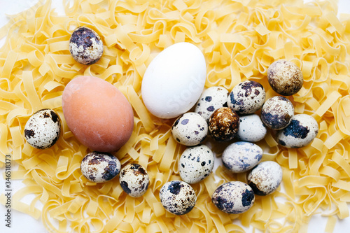 chicken and quail eggs in a nest on pasta background, family concept, selective focus