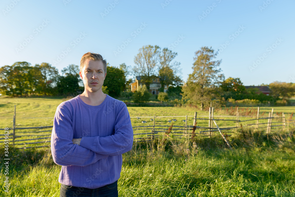 Young handsome man standing in peaceful grassy plain with nature