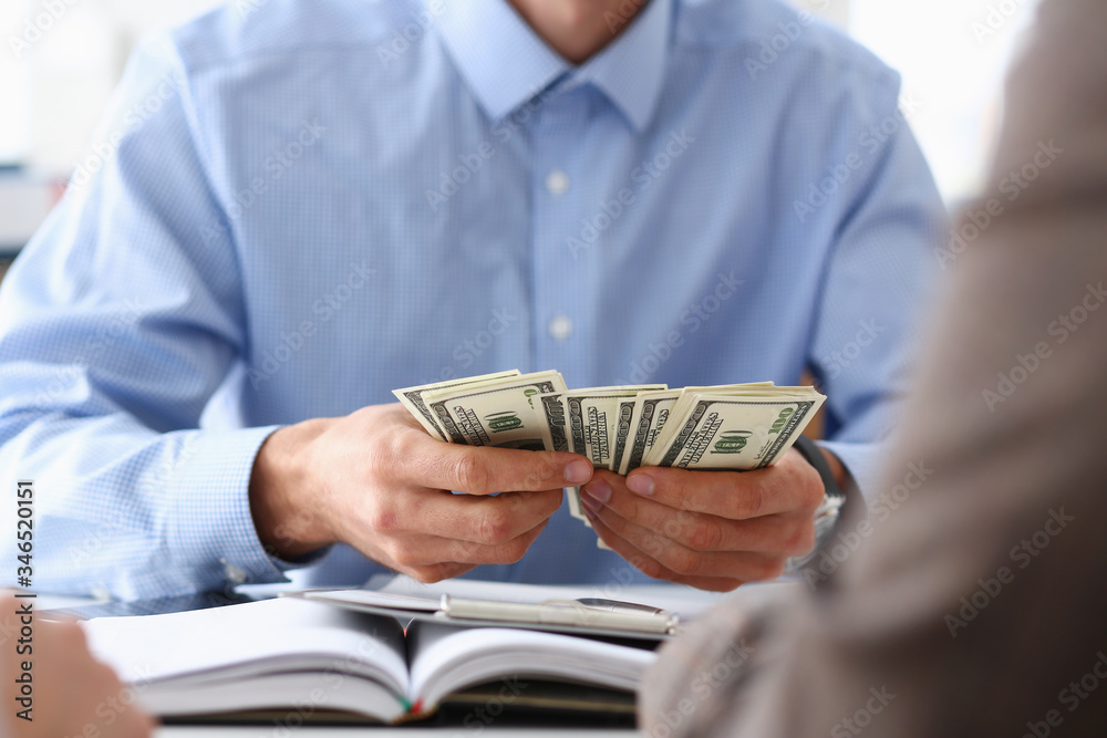 The businessman considers cash dollars in the office The businessman considers cash dollars in the office