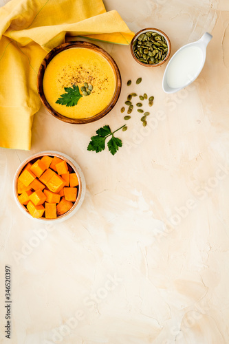 Pumpkin soup on beige table top view. Ingredients in bowls. Copy space © 279photo