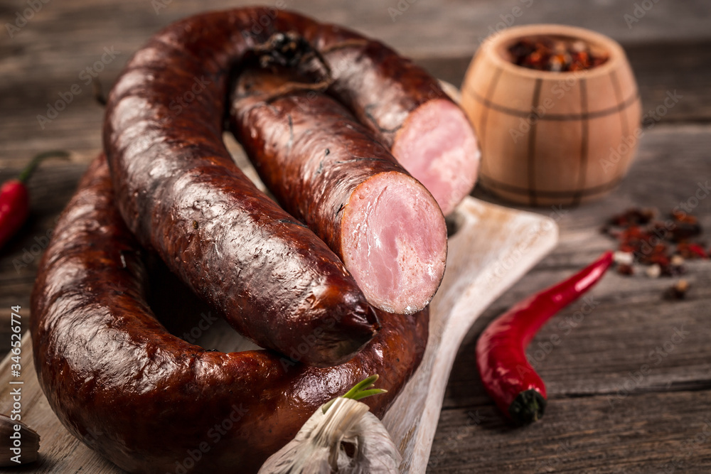 Smoked sausage on a wooden rustic table product from organic farm, produced by traditional methods. Food recipe background. Close up Smoked sausage on a wooden rustic table product from organic farm, produced by traditional methods. Food recipe background. Close up