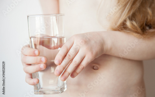 Little caucasian girl holds a glass of drinking water