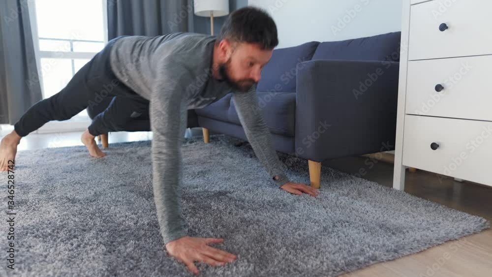 Caucasian man does exercise at home during quarantine due to COVID-19