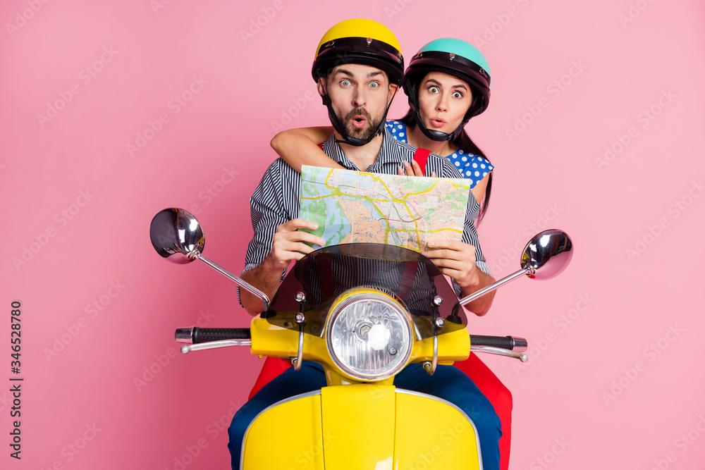 Portrait of his he her she nice attractive funny amazed couple driving moped searching address on paper map way rout journey road adventure isolated over pink pastel color background
