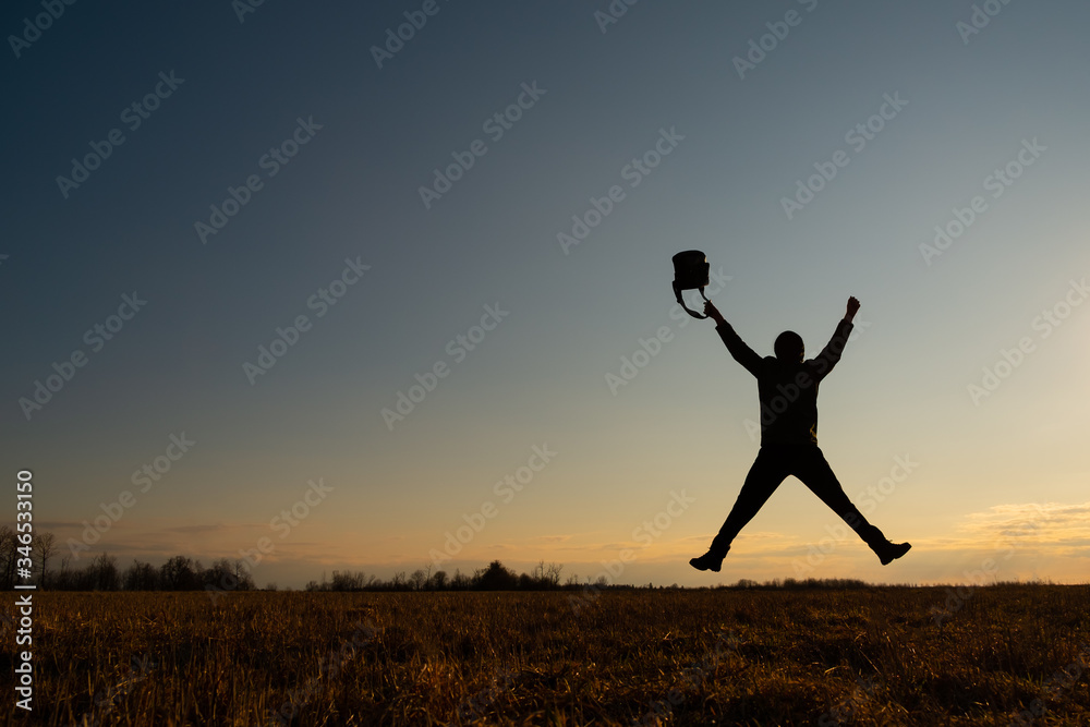 The contour of a man against the sky. The man jumped, stretching his arms and legs in the shape of a star. He has a bag in his hand. Joy concept The contour of a man against the sky. The man jumped, stretching his arms and legs in the shape of a star. He has a bag in his hand. Joy concept