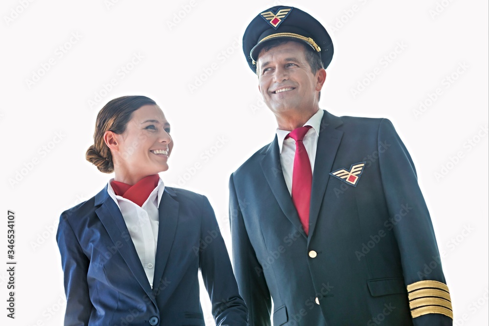 Cutouts of mature pilot talking while walking with beautiful stewardess Cutouts of mature pilot talking while walking with beautiful stewardess