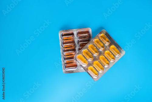 yellow and brown supplement in capsules top view with blue background