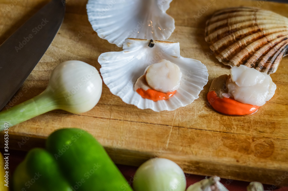 raw scallops and vegetables on a wooden cutting board close up - preparing food