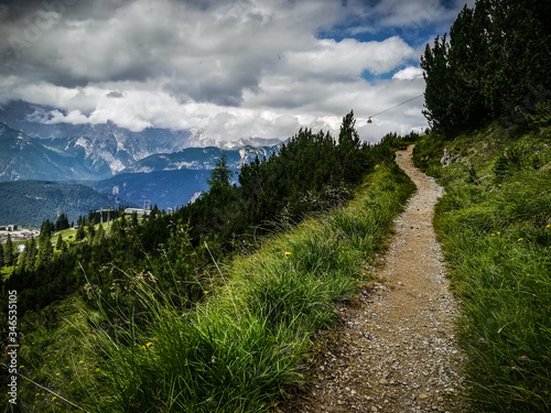 Dramatic vintage view of narrow gravel trekking trail, grass close-up across mountain peak