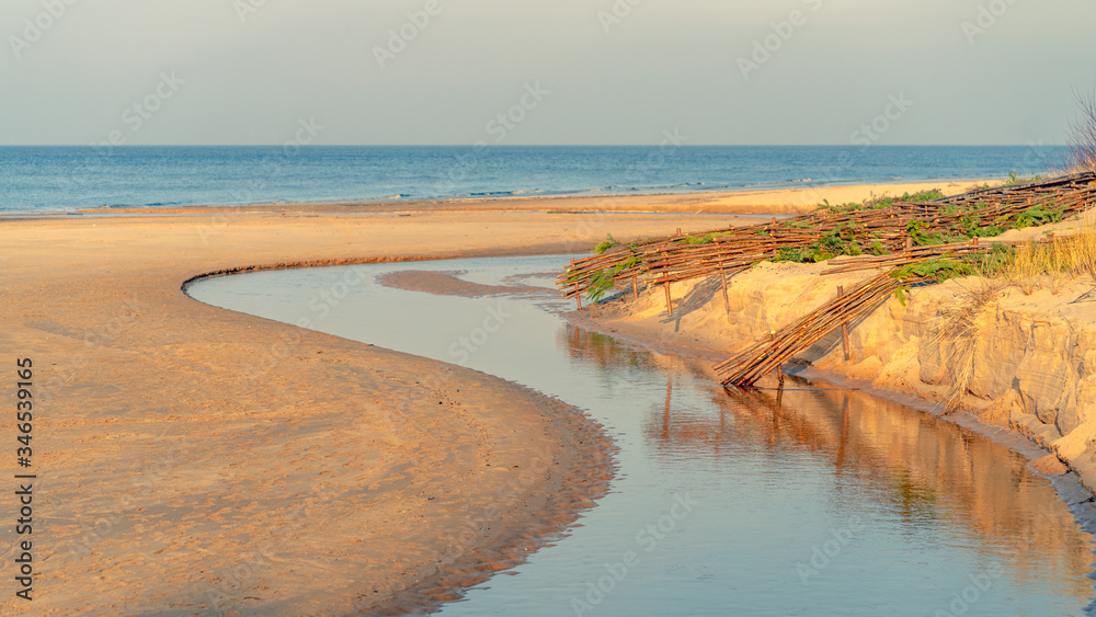 A river in sand dunes flows into the sea