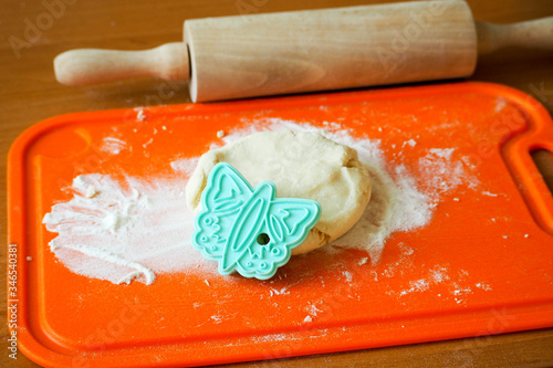 dodough from rice flour cottage cheese and eggs for cookies on a plastic orange Board and a blue butterfly shape. a Board with dough, a wooden rolling pugh from rice flour cottage cheese and eggs for  photo